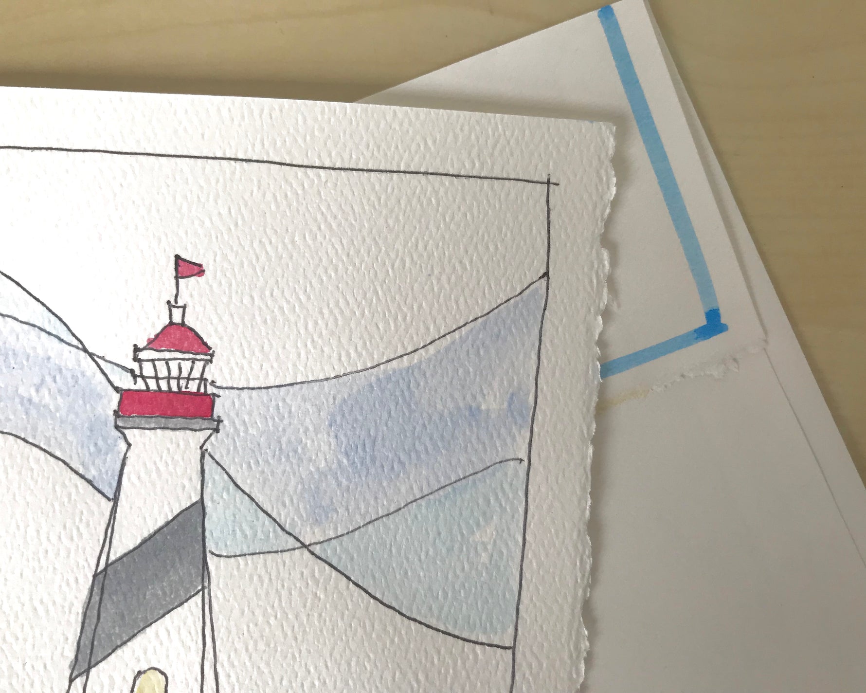 Detail of watercolor and drawing of top of ighthouse and deckled edge card ontop of painted edged envelope