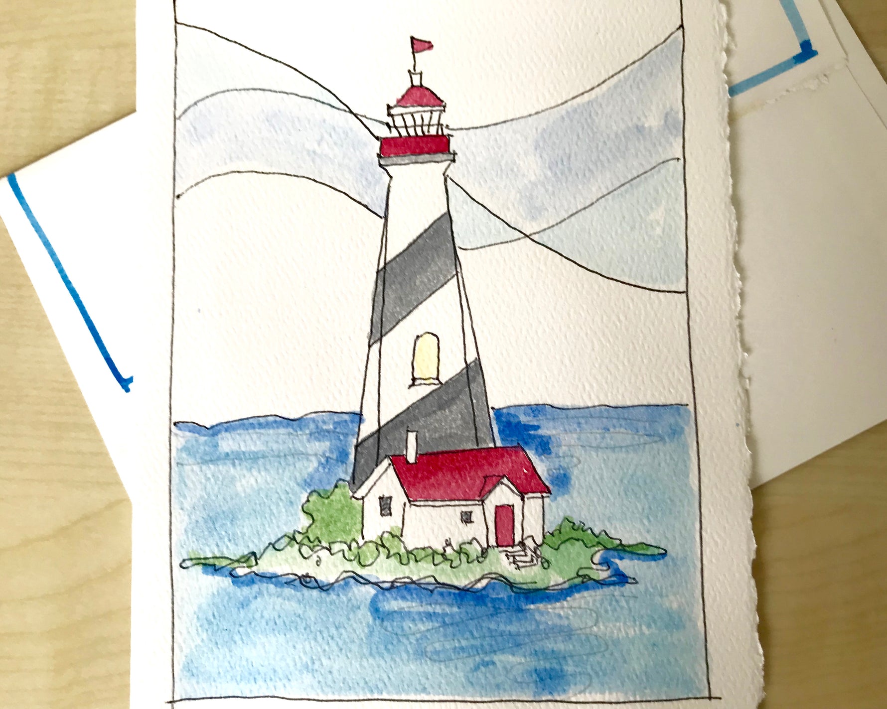Close up details of watercolor and line drawing of island lighthouse on a deckled edge card